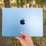 A person is holding a blue apple laptop.