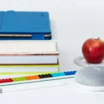 honeycrisp apple fruit near books and chalk Google Home Mini smart speaker