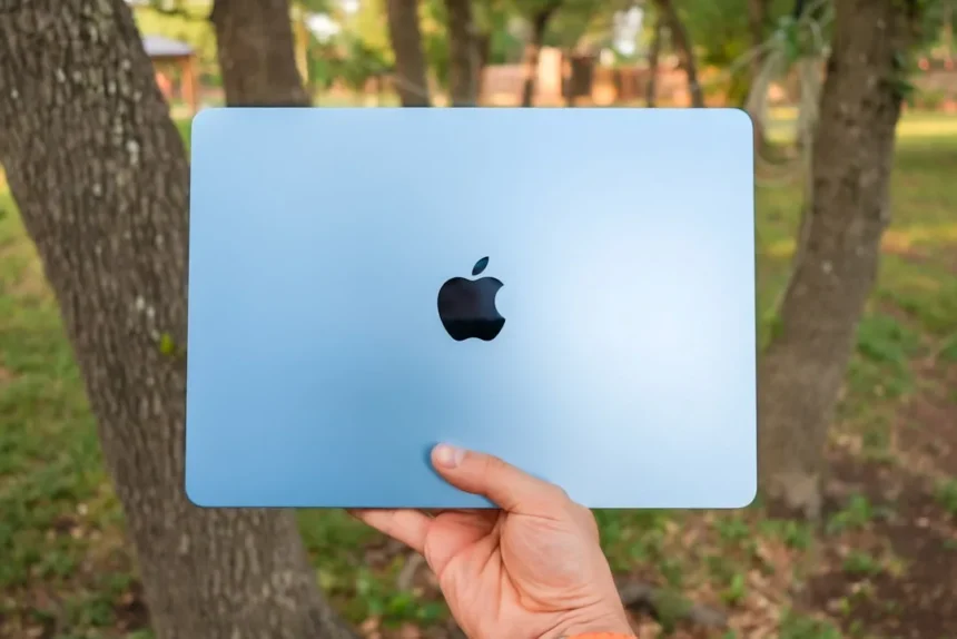 A person is holding a blue apple laptop.