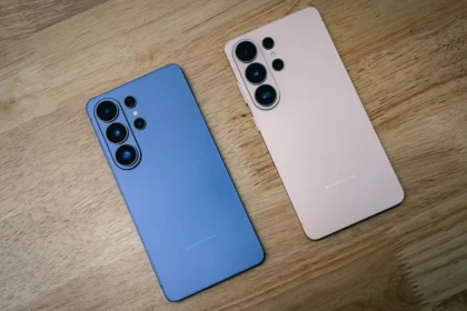 Two smartphones, blue and pink, on a wooden surface