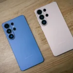 Two smartphones, blue and pink, on a wooden surface