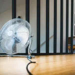 a fan sitting on the floor in front of a stair case