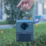 a hand holding a small camera in front of a building
