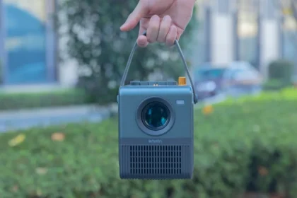 a hand holding a small camera in front of a building