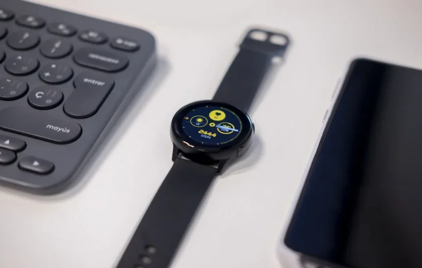 round black watch beside gray keyboard