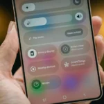 Person holding a smartphone displaying a settings menu