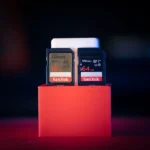 a couple of cell phones sitting on top of a red stand