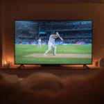 Cricket match playing on a television screen at night.