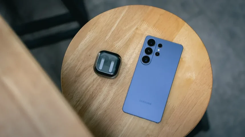 A blue smartphone and earbuds on a wooden table