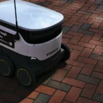 a white and black robot sitting on top of a brick road