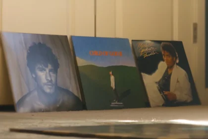 Three vinyl record album covers displayed upright on the floor.