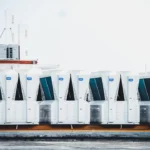 a row of portable air conditioners sitting on top of a roof