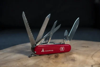 A red swiss army knife sitting on top of a wooden table